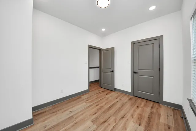 a view of an empty room with wooden floor and closet