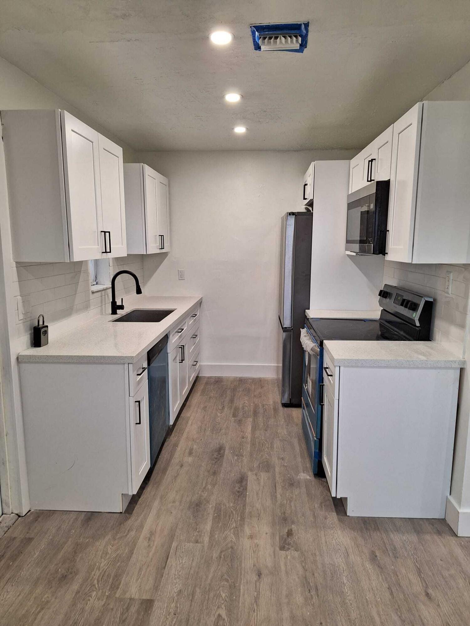 a kitchen that has a lot of cabinets in it and wooden floors