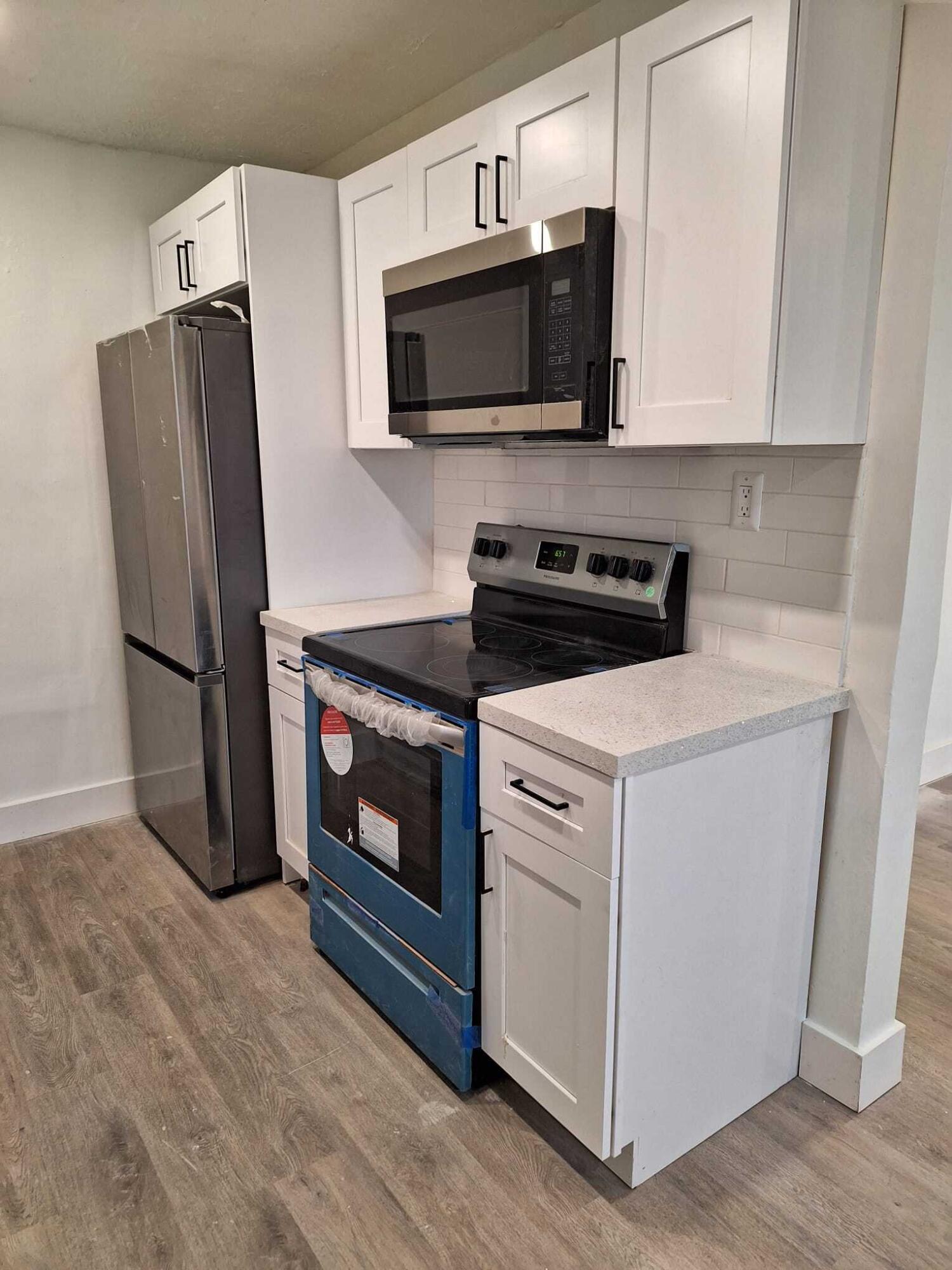 1000 West 1st Street Riviera Beach, FL 33404 - Photo 2 of 8 a kitchen with stainless steel appliances white cabinets a stove a microwave and a refrigerator