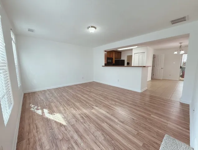 a view of empty room with wooden floor and windows