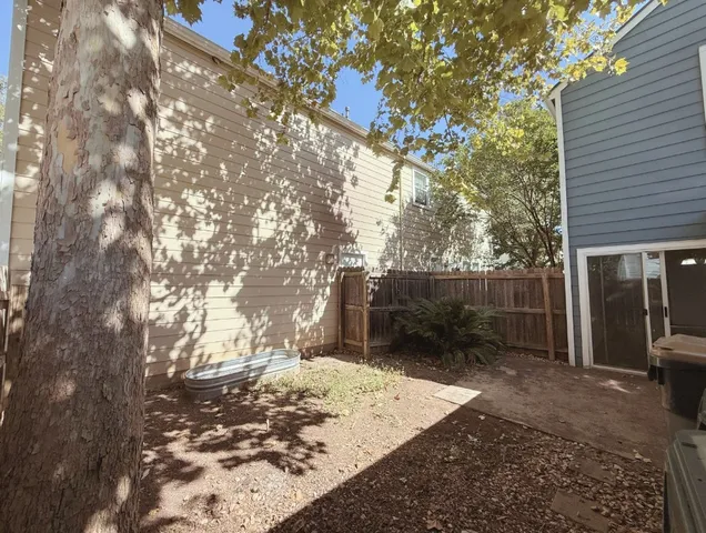 a view of backyard with wooden fence and large trees