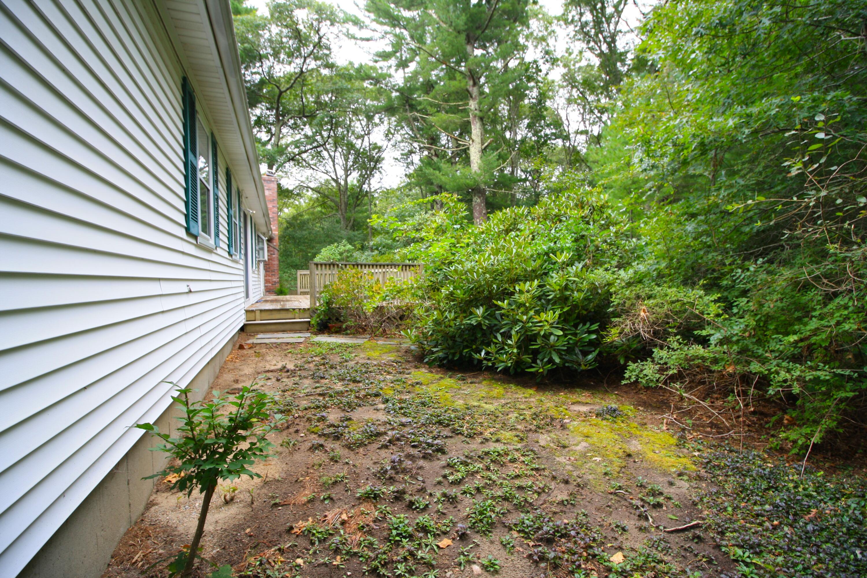 177 Thistle Drive Centerville, MA 02632 - Photo 22 of 22 a view of a yard with plants and wooden fence