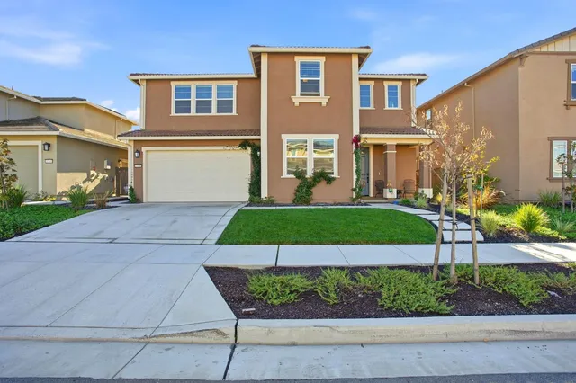 a front view of a house with a yard and potted plants