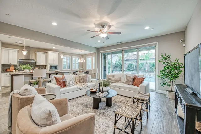 a living room with furniture ceiling fan and a large window