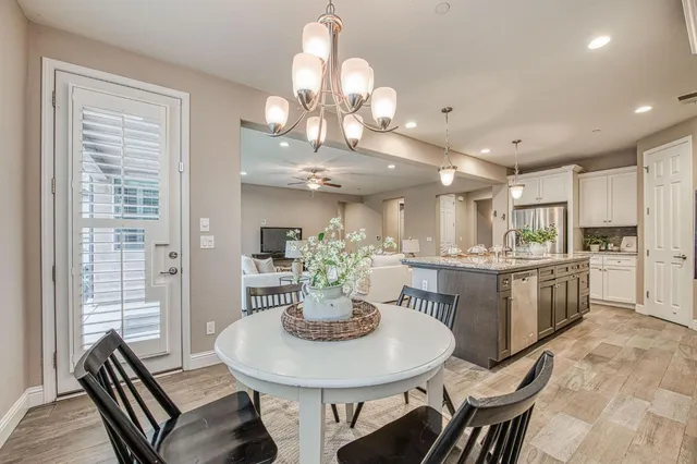a kitchen with a dining table cabinets wooden floor and stainless steel appliances