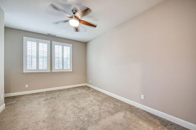an empty room with windows and ceiling fan