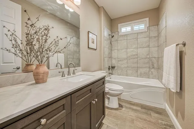 a bathroom with a granite countertop sink a toilet and bathtub