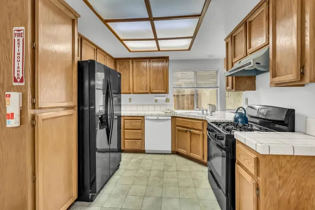 a kitchen with stainless steel appliances granite countertop a refrigerator a sink dishwasher a stove with wooden cabinets