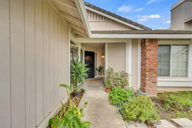 a front view of yellow house with potted plants