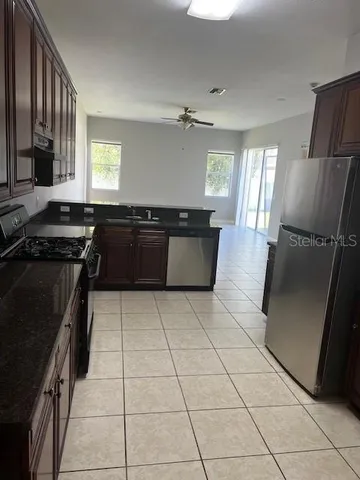a kitchen with granite countertop a stove a sink a counter top space and cabinets