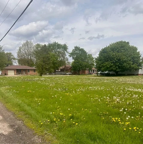 a view of a green field with wooden fence