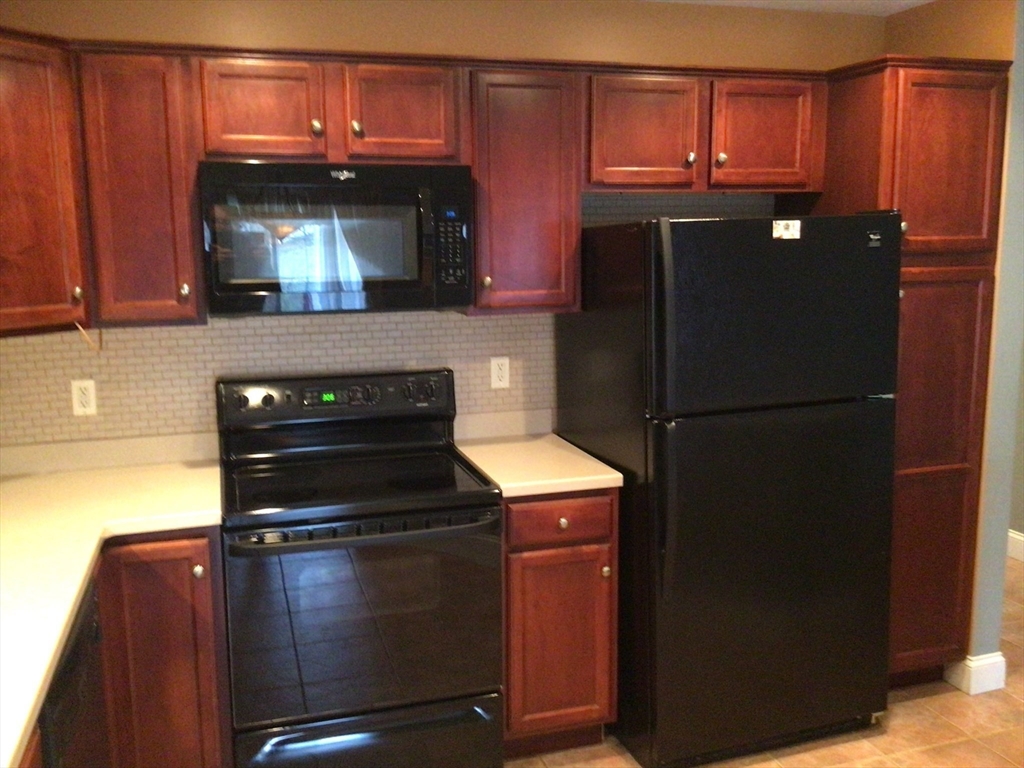 4 Village Way, Unit 4 Rutland, MA 01543 - Photo 10 of 33 a kitchen with granite countertop wooden cabinets and refrigerator