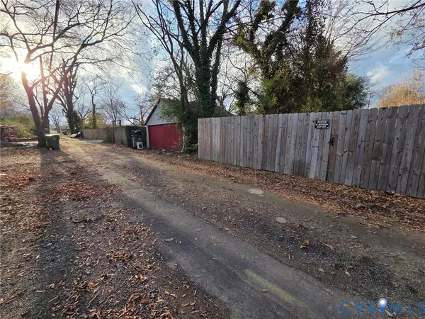 a view of backyard with large trees and wooden fence