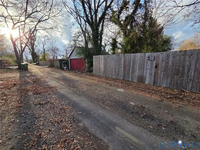 a view of backyard with large trees and wooden fence