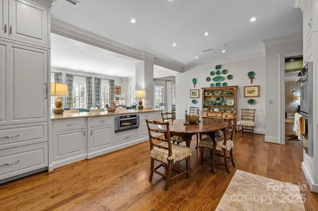 a kitchen with stainless steel appliances kitchen island granite countertop a table chairs sink and cabinets