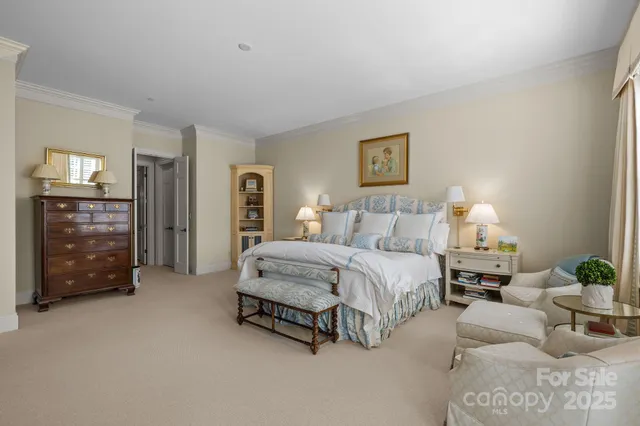 a spacious bedroom with a bed a couch and a chandelier