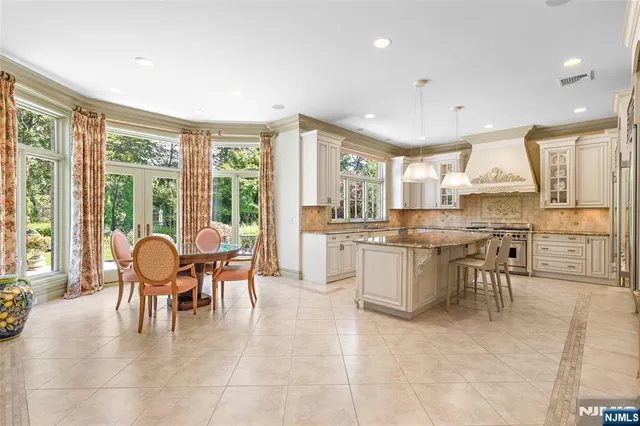 a dining hall with stainless steel appliances kitchen island granite countertop a stove a sink a dining table and chairs