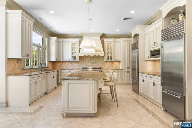 a kitchen with stainless steel appliances granite countertop a sink a stove a refrigerator and a refrigerator
