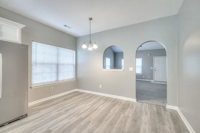 an empty room with chandelier fan and windows