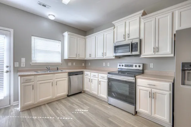 a kitchen with stainless steel appliances granite countertop a stove a sink and white cabinets