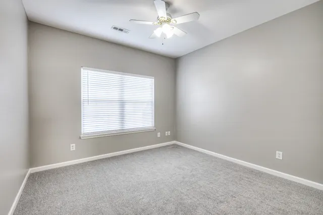 an empty room with a window and a fan