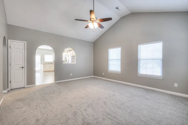 a view of a big room with windows and chandelier fan