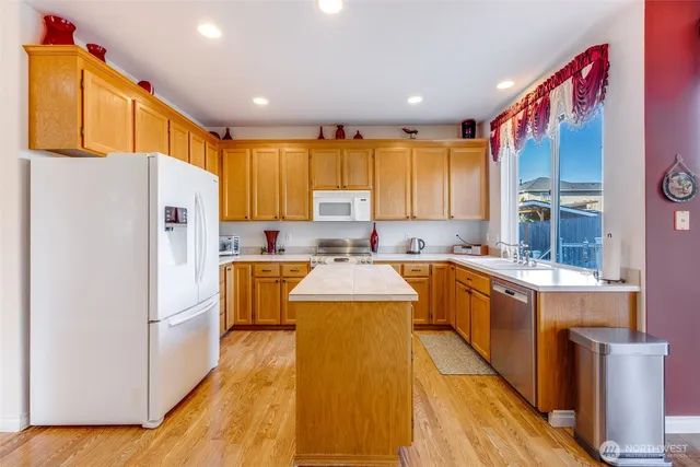 a kitchen with a refrigerator a stove top oven a sink and cabinets