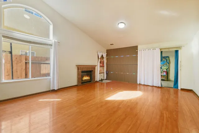 a view of an empty room with a window and wooden floor