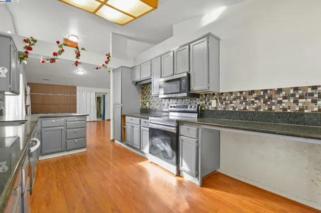 a kitchen with stainless steel appliances a sink cabinets and wooden floor