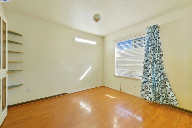 a view of an empty room with window and wooden floor