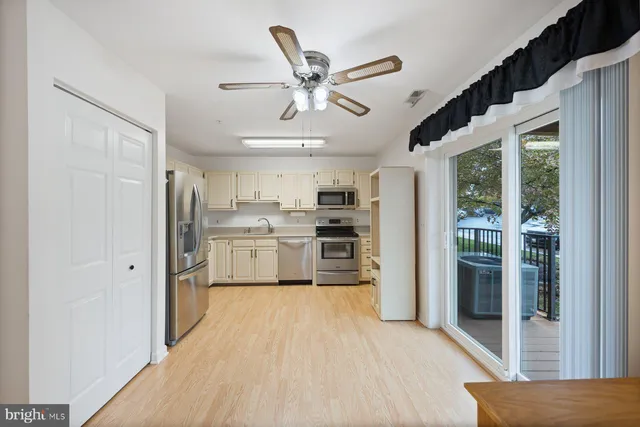 a kitchen with stainless steel appliances a refrigerator a sink dishwasher a stove and white cabinets with wooden floor