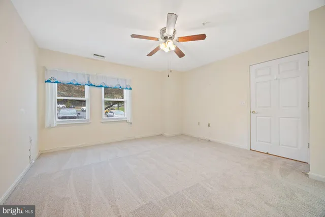 an empty room with windows and ceiling fan