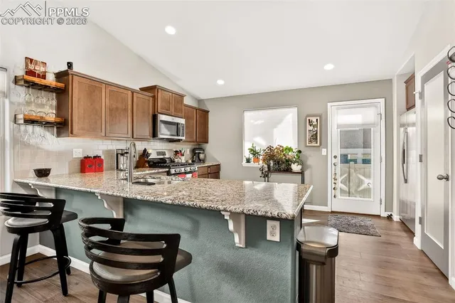 a kitchen with stainless steel appliances granite countertop a stove top oven a sink dishwasher and cabinets with wooden floor