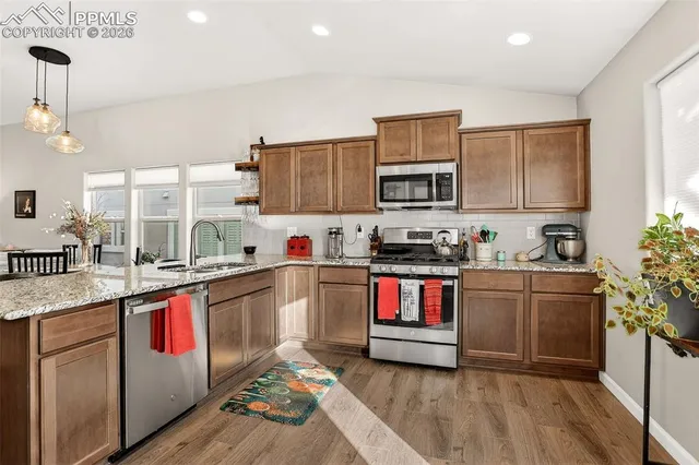 a kitchen with stainless steel appliances granite countertop a stove a sink and a microwave