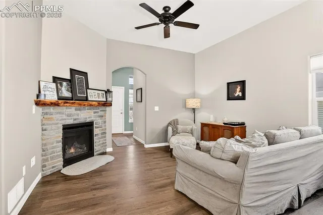 a living room with furniture a fireplace and a ceiling fan