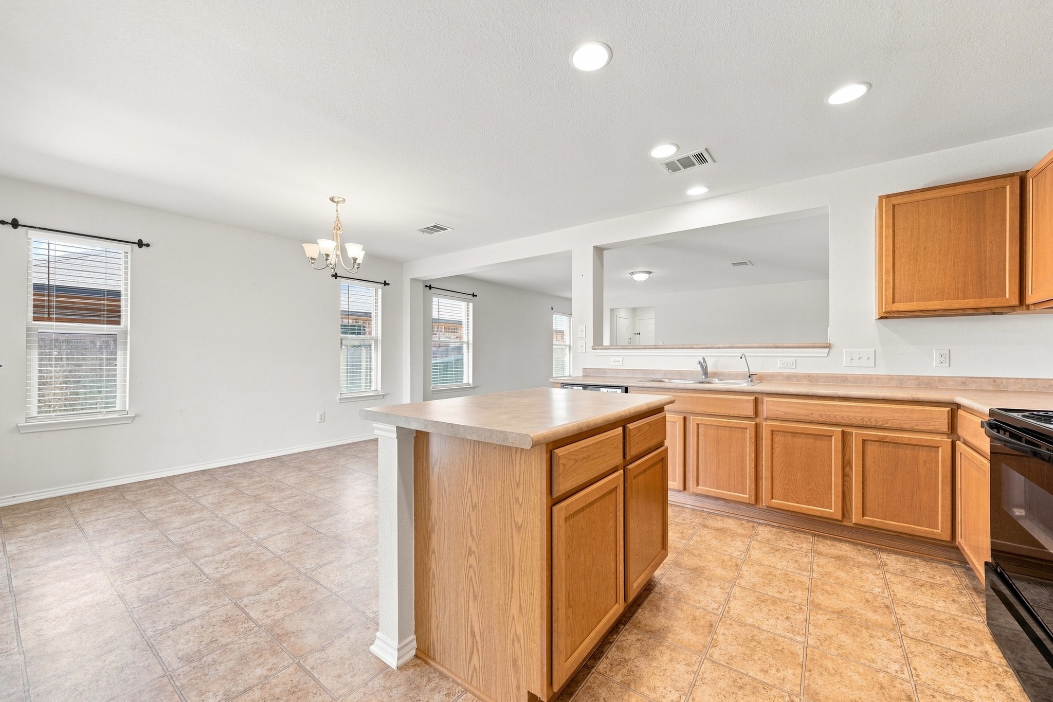 Tiled flooring anchors this open kitchen layout featuring a central island and a pass-through wall.