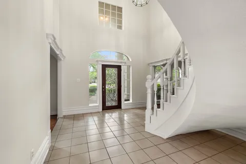 an empty room with wooden floor fireplace and windows