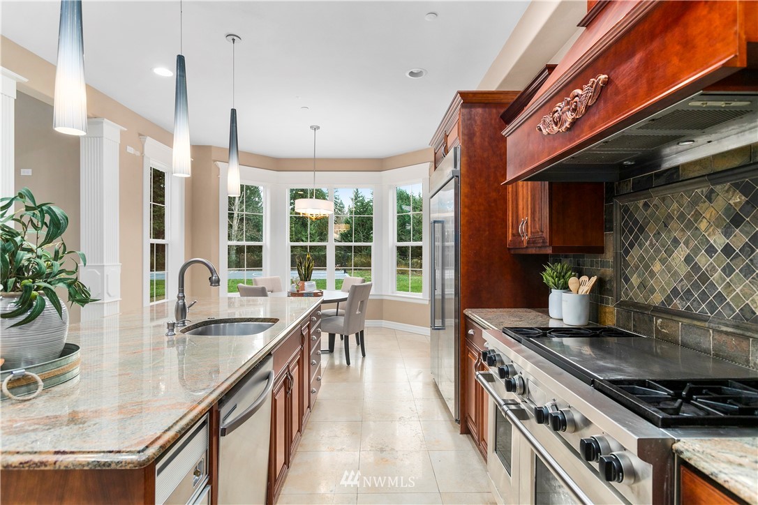 20630 Southeast 216th Street Maple Valley, WA 98038 - Photo 12 of 40 a kitchen with stainless steel appliances granite countertop a sink a stove and a wooden floors