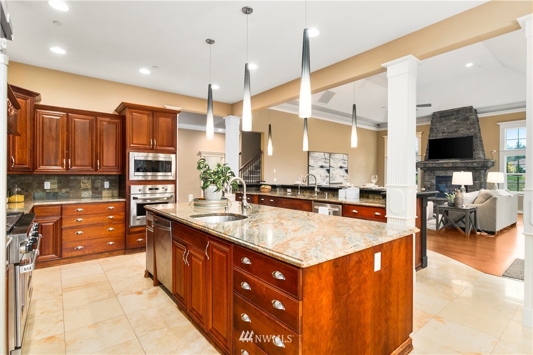 20630 Southeast 216th Street Maple Valley, WA 98038 - Photo 13 of 40 a large kitchen with kitchen island a large counter top space a sink stainless steel appliances and cabinets