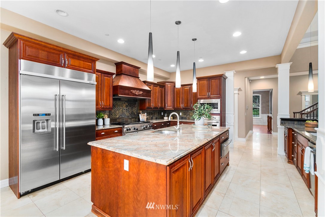 20630 Southeast 216th Street Maple Valley, WA 98038 - Photo 14 of 40 a kitchen with stainless steel appliances granite countertop a kitchen island a refrigerator a stove and a sink