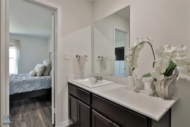 a en suite bathroom with a granite countertop sink and a mirror