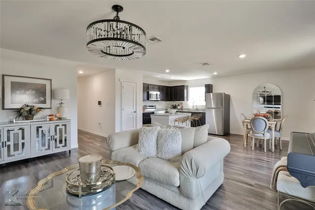 a living room with furniture a table and kitchen view