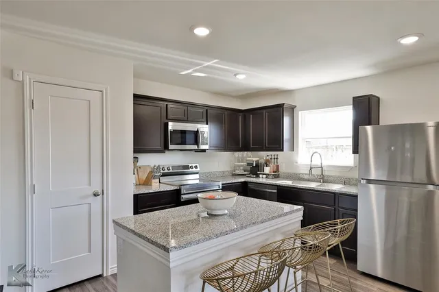 a kitchen with a sink a stove a refrigerator and white cabinets
