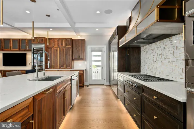 a large kitchen with a large counter top a sink stainless steel appliances and cabinets