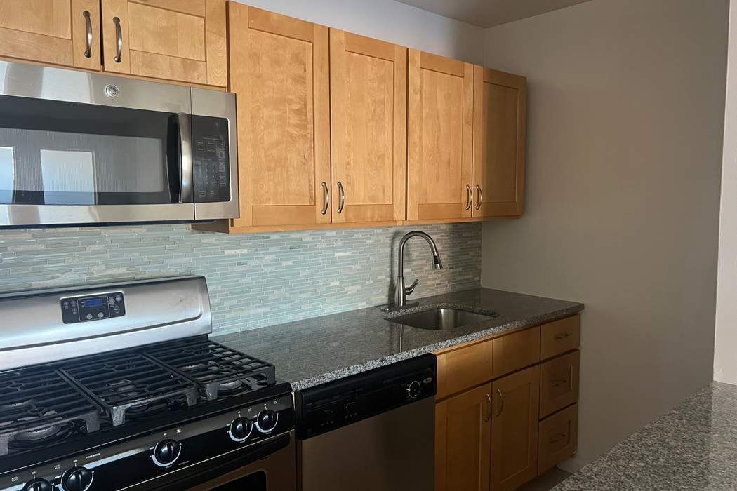 222 West 14th Street, Unit 6H Manhattan, NY 10011 - Photo 5 of 14 a kitchen with granite countertop a stove sink and cabinets