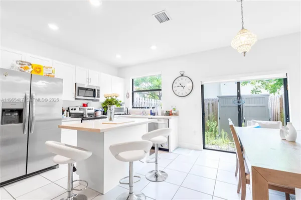 a kitchen with stainless steel appliances kitchen island granite countertop a refrigerator a stove and a dining table with wooden floor