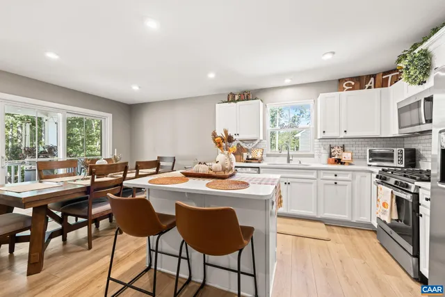 a kitchen with stainless steel appliances granite countertop a stove a sink a refrigerator and white cabinets with wooden floor