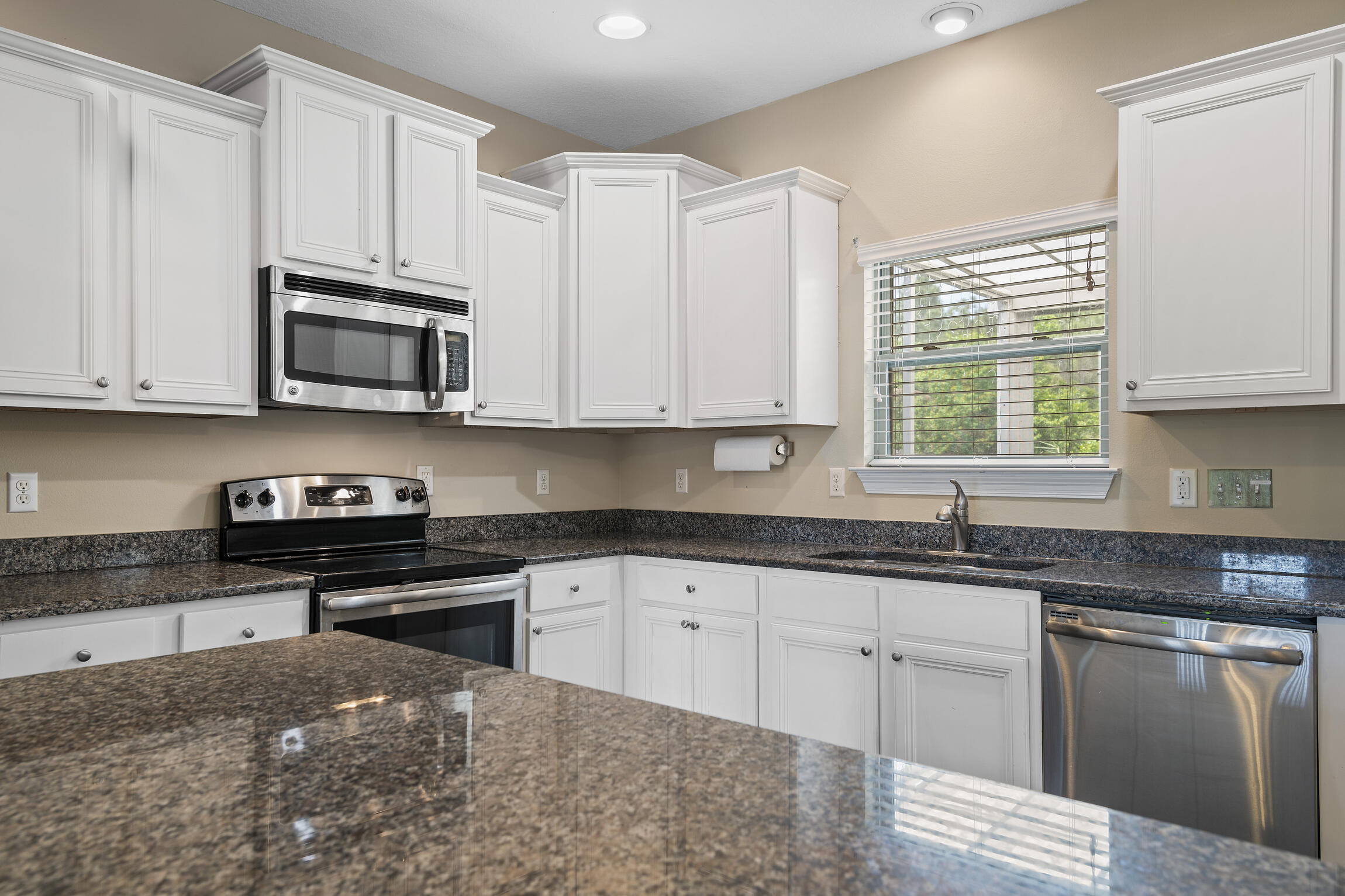 159 Lullaby Loop Santa Rosa Beach, FL 32459 - Photo 7 of 42 a kitchen with granite countertop white cabinets sink and stainless steel appliances
