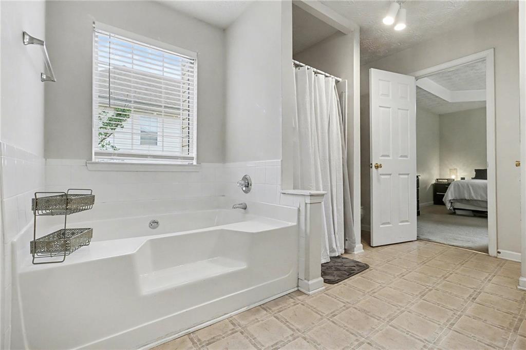 1777 Cutters Mill Way Lithonia, GA 30058 - Photo 14 of 23 a bathroom with a tub a sink and a large mirror