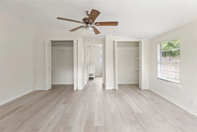 a view of empty room with wooden floor and fan